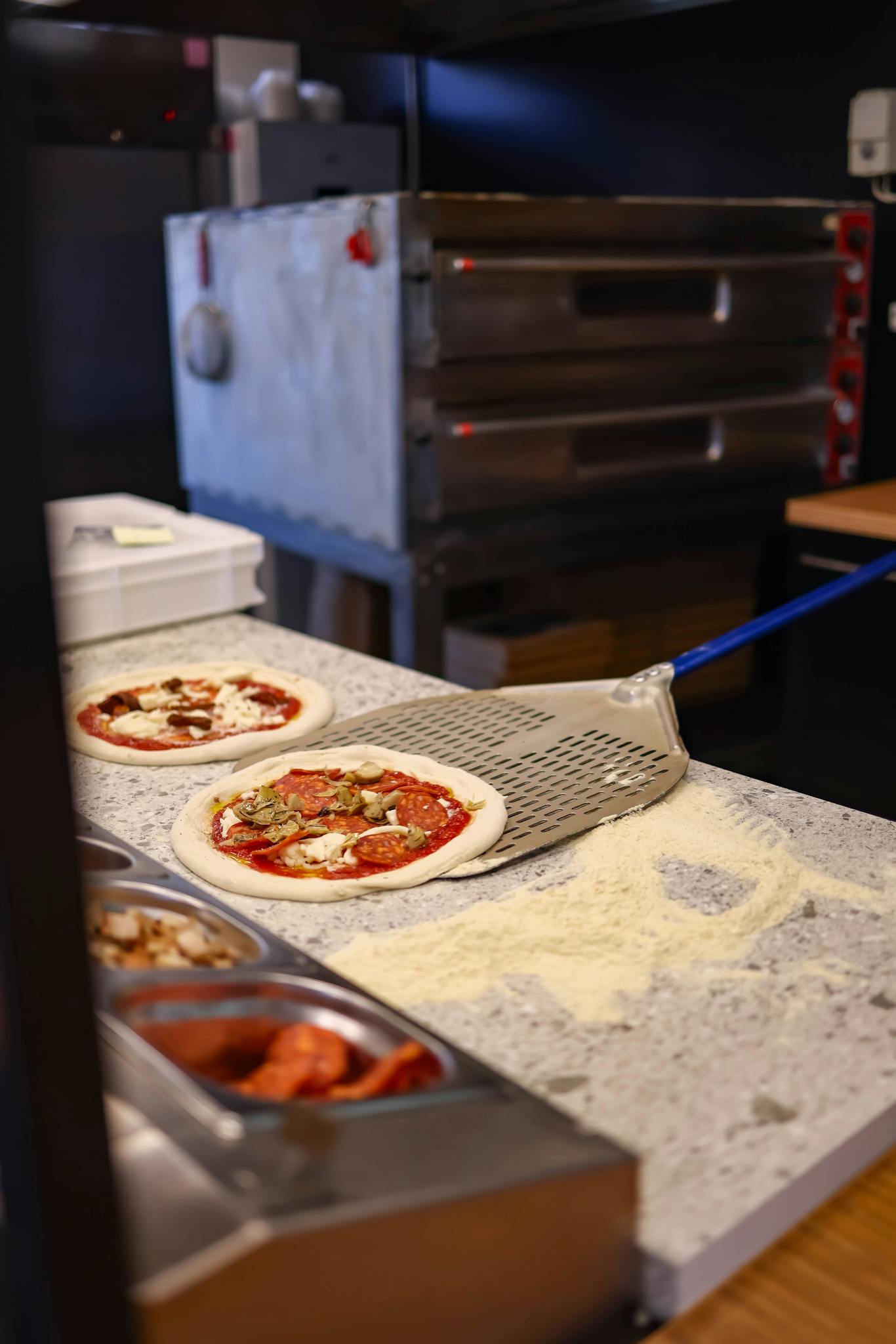 Freshly prepared pizza ready for baking in a modern kitchen setting with a pizza oven.